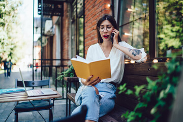 Spanish freelancer in classic glasses checking information from memo textbook for discussing...