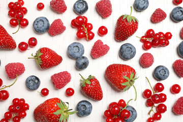 Fototapeta na wymiar Different fresh berries on white wooden table, flat lay