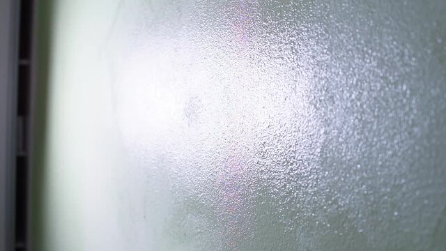 Close-up of a paint roller in motion on a wall. Apply paint to hard surfaces. Make repairs to living quarters with your hands.