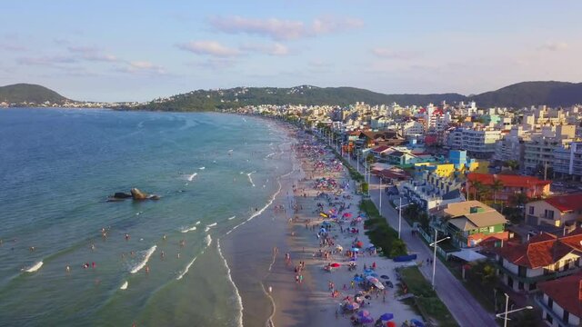 Aerial establishing shot of Bombas beach crowded with tourists enjoying at golden hour