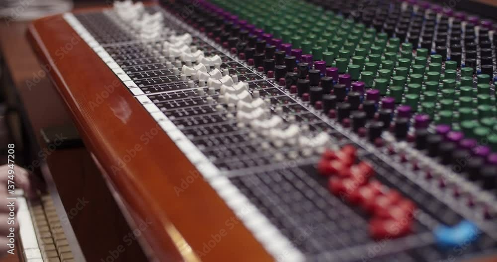 Poster man in a control room of a recording studio moving a fader with a toft console / professional record