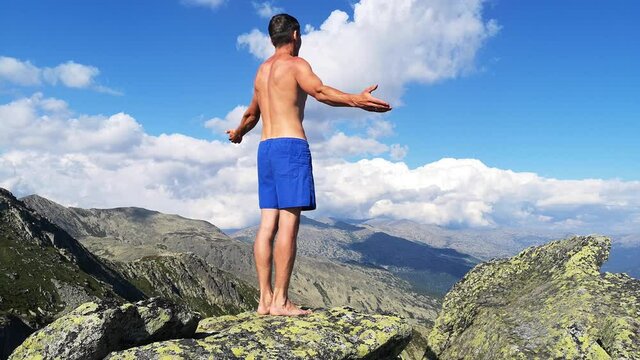 man stands on top of a mountain with open hands. at the top of the mountain, a man with his arms spread wide.