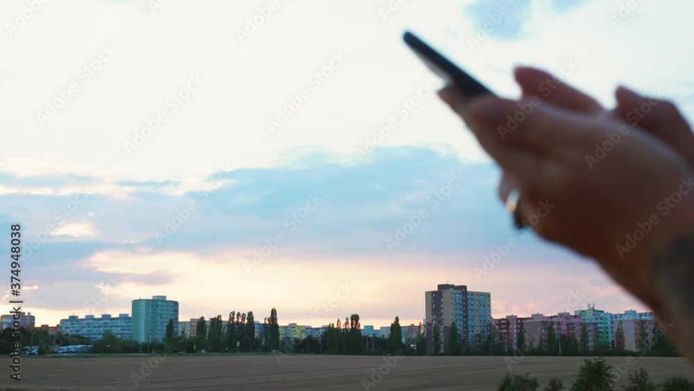 Poster the bokeh effect of using the phone in the hands of a woman on the background of the city in the eve