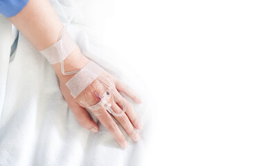 Close-up of saline solution in a patient's hand in clothing, lying on a hospital bed, the patient dripping saline on a white background.