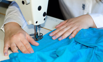 Seamstress.  woman scribbles blue fabric on  sewing machine.