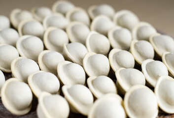 Raw dumplings on a round Board, top view. A traditional Slavic dish. Russian national food. The process of cooking dumplings. Traditional home-made food. Dough from flour for dumplings.
