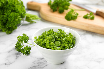 Cut curly parsley in bowl on white marble table
