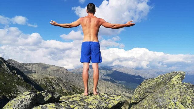 man stands on top of a mountain with open hands. at the top of the mountain, a man with his arms spread wide.