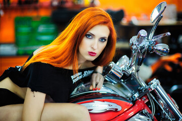 Naklejka na ściany i meble Portrait of charming young woman with red hair near a motorcycle