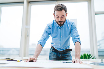 Concentrated man drafting by table in office