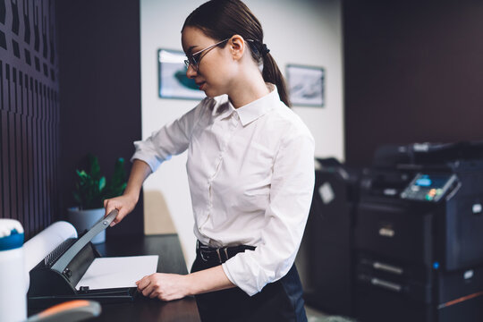 Female office worker cutting paper in office