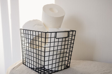 Toilet paper rolls storage in a black metal basket on a white background. Minimal interior design concept