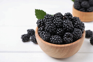 Fresh ripe blackberries in bowl on white wooden table, closeup