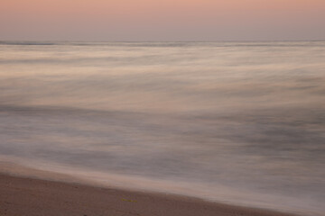 Seascape. Waves and surf. Sunset and dawn at sea. Calm on the ocean. Beautiful sky and clouds illuminated by the sun. Natural background. Summer time. Long exposure blurred water movement.