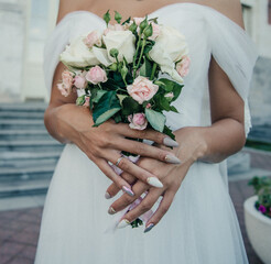 Obraz na płótnie Canvas bride's hand with an elegant wedding ring with white gold diamonds on a bouquet of their peonies