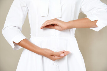 Close up cropped photo of woman's slim stomach with her hands showing a balance in microflora in a white robe.
