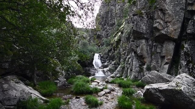 Small and beautiful waterfall in the middle of a very rocky area with lots of nature around