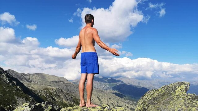 man stands on top of a mountain with open hands. at the top of the mountain, a man with his arms spread wide.