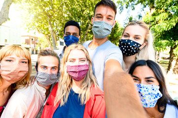 Multiracial young people taking selfie while wearing protective masks