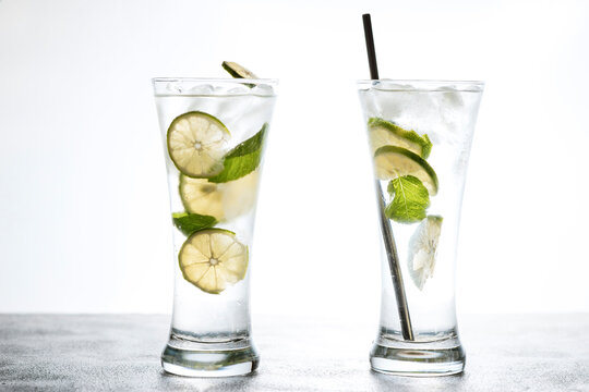 Cold refreshing beverage with sliced lime ripes and ice reverse light image in studio with white illuminated background