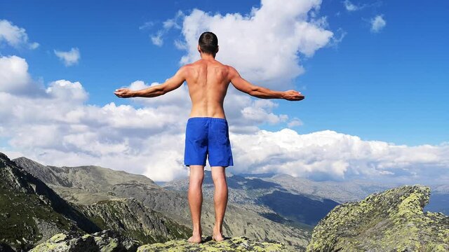 man stands on top of a mountain with open hands. at the top of the mountain, a man with his arms spread wide.