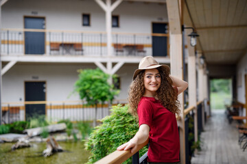 Young woman standing outdoors by hotel on holiday, relaxing.