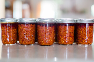 Jars of Thai Chili Paste / Chili Sauce on a kitchen counter. This spicy chili jam is called chili oil, or Naam Prik Phao and Vietnamese Lemongrass Chili Garlic Sate (