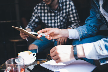 Crop colleagues working on project in coffeehouse
