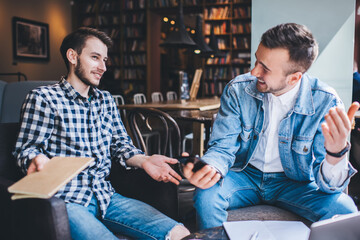 Laughing friends talking while sitting in  coffee shop