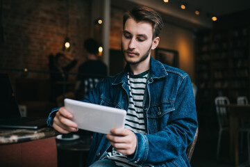 Freelance adult male surfing tablet in cafe