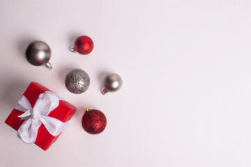 red gift box with white ribbon and silver and red christmas balls 