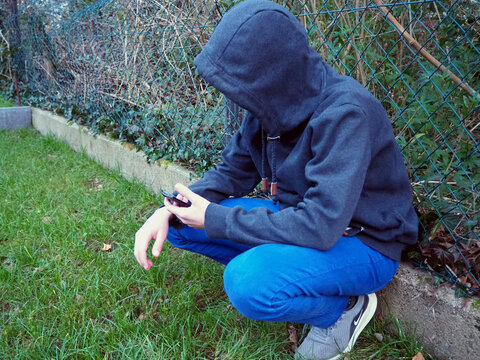Herumlungern, das Smartphone beobachten und unerkannt bleiben: Ein Jugendlicher checkt die Lage am Handy - Was geht ab?