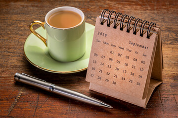 September 2020 - spiral desktop calendar on a rustic wood table with a cup of coffee