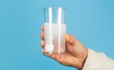 Glass of water tablet. Glass with efervescent tablet in water with bubbles. White pill and a glass of water in man hands. Health concept. Close up of man holding a pill