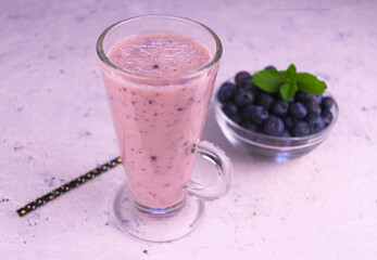 
Delicious blueberry smoothie with fresh berries yogurt in a tall glass on a white background.