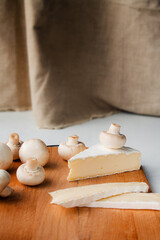 Cheese brie slices on a wooden board with mushrooms. Copy space on top. Vertical.