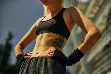 Cropped image of sport belly athletic female with black hand wraps outdoor