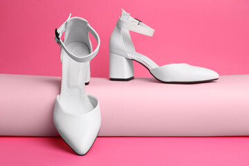Stylish white female shoes on pink background
