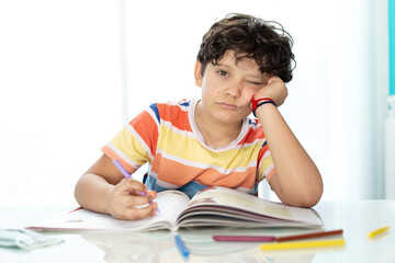 Little boy doing homework showing bored expression. Concept of study and education.