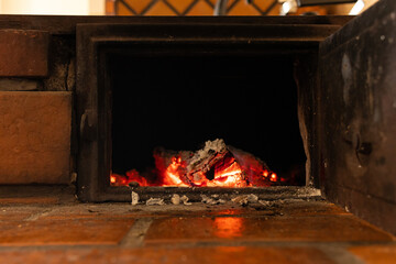 Firewood stove with bricks, highlighting the ember. Black orange color and embers in the center of...