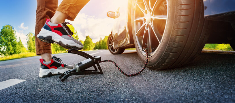 Driver using a foot pump to inflate a tire