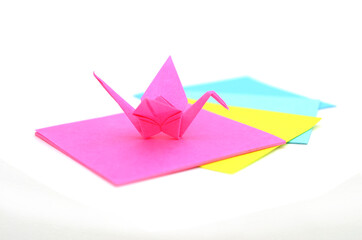 A pink origami crane with paper sheets