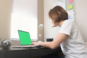 Fototapeta premium woman looking at the computer green screen for online class learning.