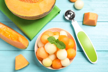 Melon balls and mint in bowl on light blue table, flat lay