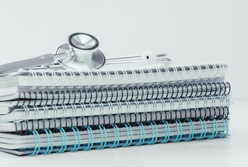 Medical or healthcare concept. stethoscope on top of pile of spiral notepads. Medical study or research, paperwork. Learning.