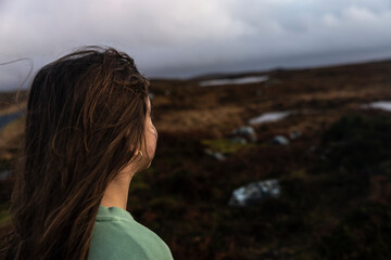 Teenage girl looking at an irish meadow landscape in Ireland