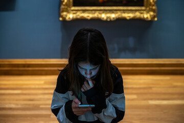 Teenage girl looking at her mobile phone in a museum