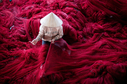 Woman repairing fishing nets, Vietnam
