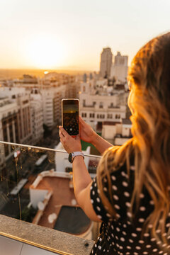 Young blonde woman taking a photo with her phone in madrid