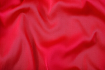 Background from red flowing glossy fabric. Fabric texture.